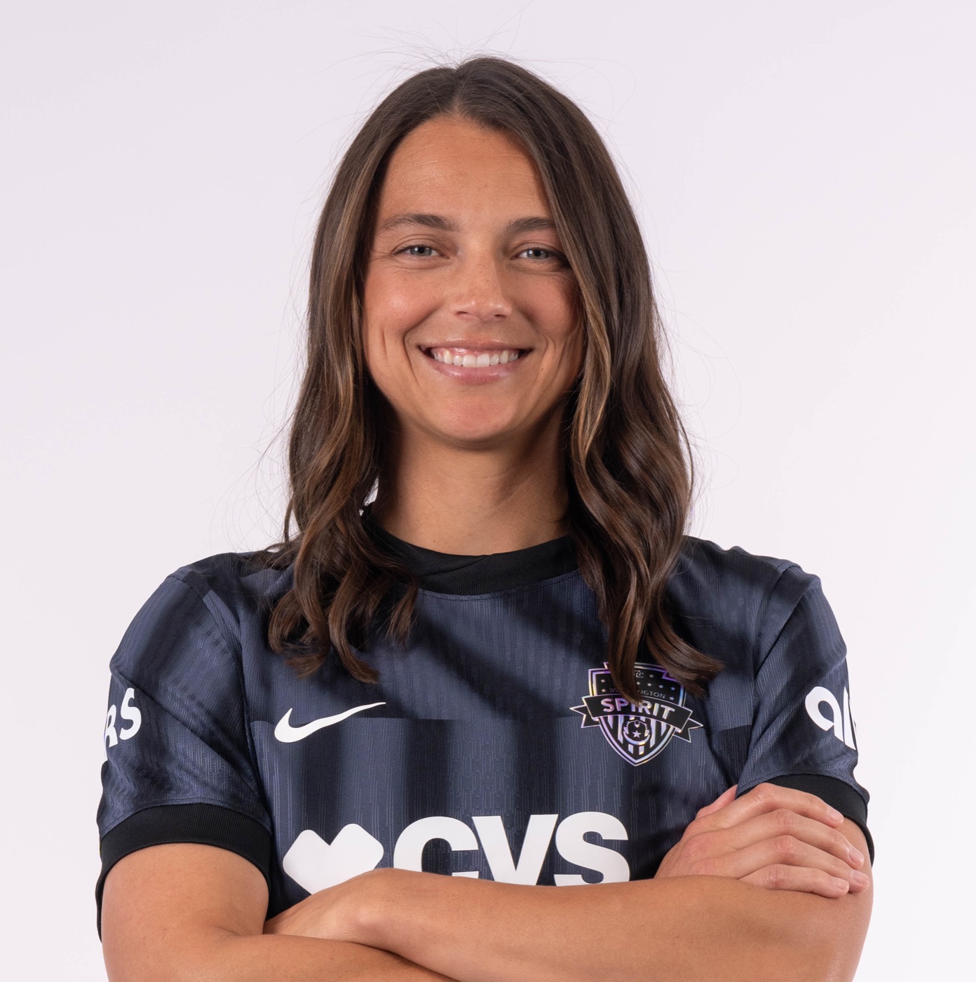 Ashley Hatch in her Washington Spirit kit, arms crossed, smiling at the camera.