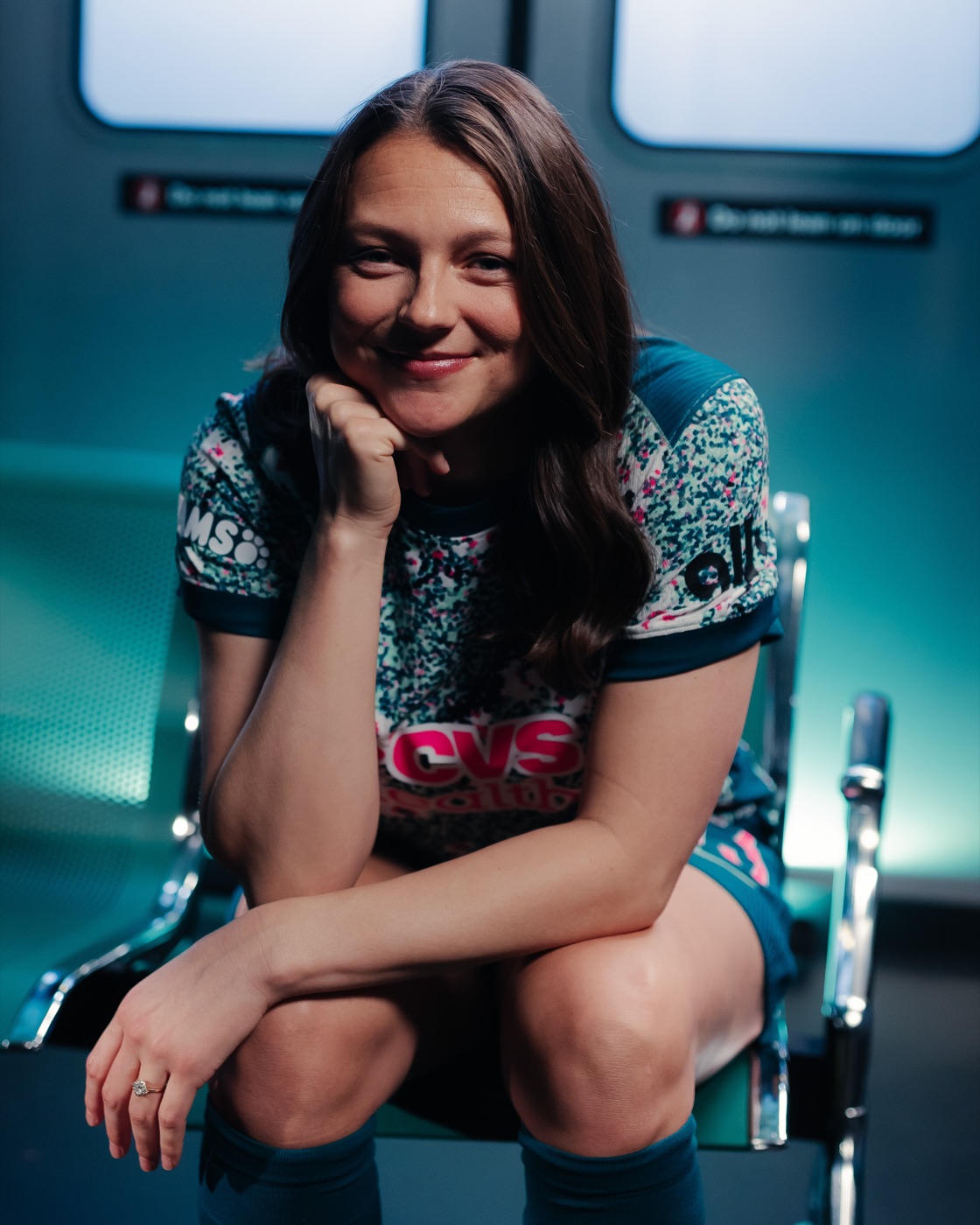Ashley Hatch seated, leaning forward with her chin on her hand, smiling.